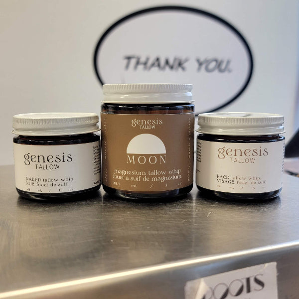 Three jars of genesis tallow products on a metallic surface with 'THANK YOU' sign in the background.